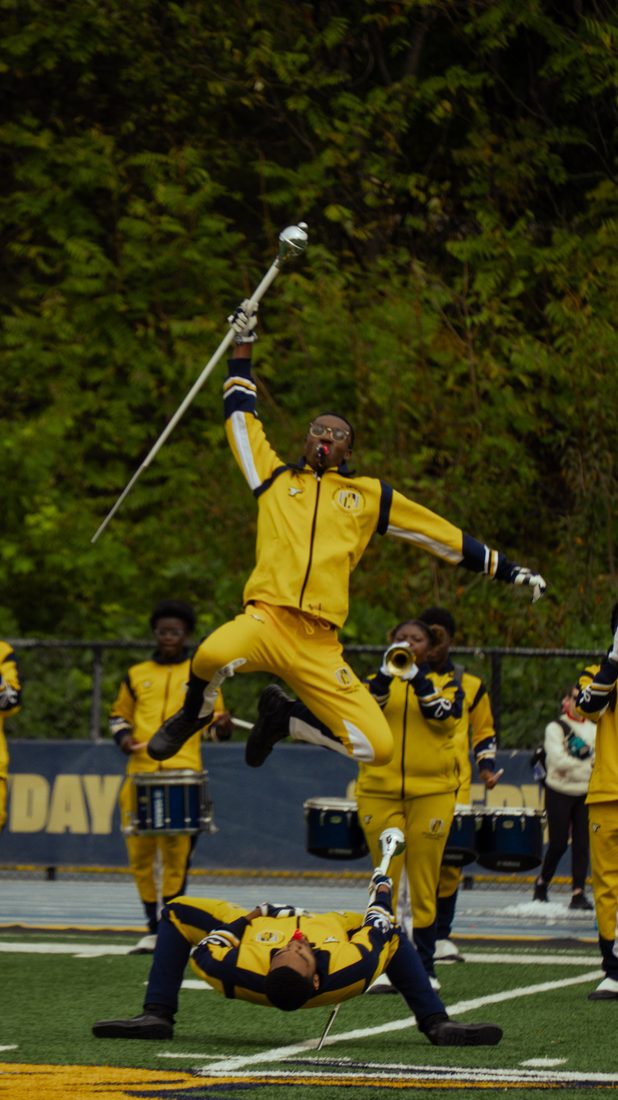A drum major leaping during a field performance